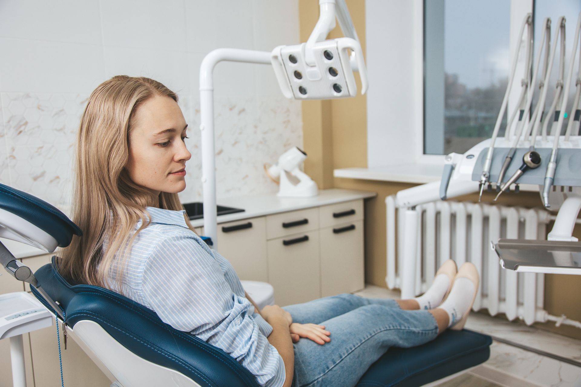 Woman reclining in a dentist chair in a bright dental clinic, with dental equipment nearby