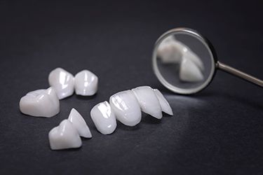A close up of dental crowns and a dental mirror on a table.