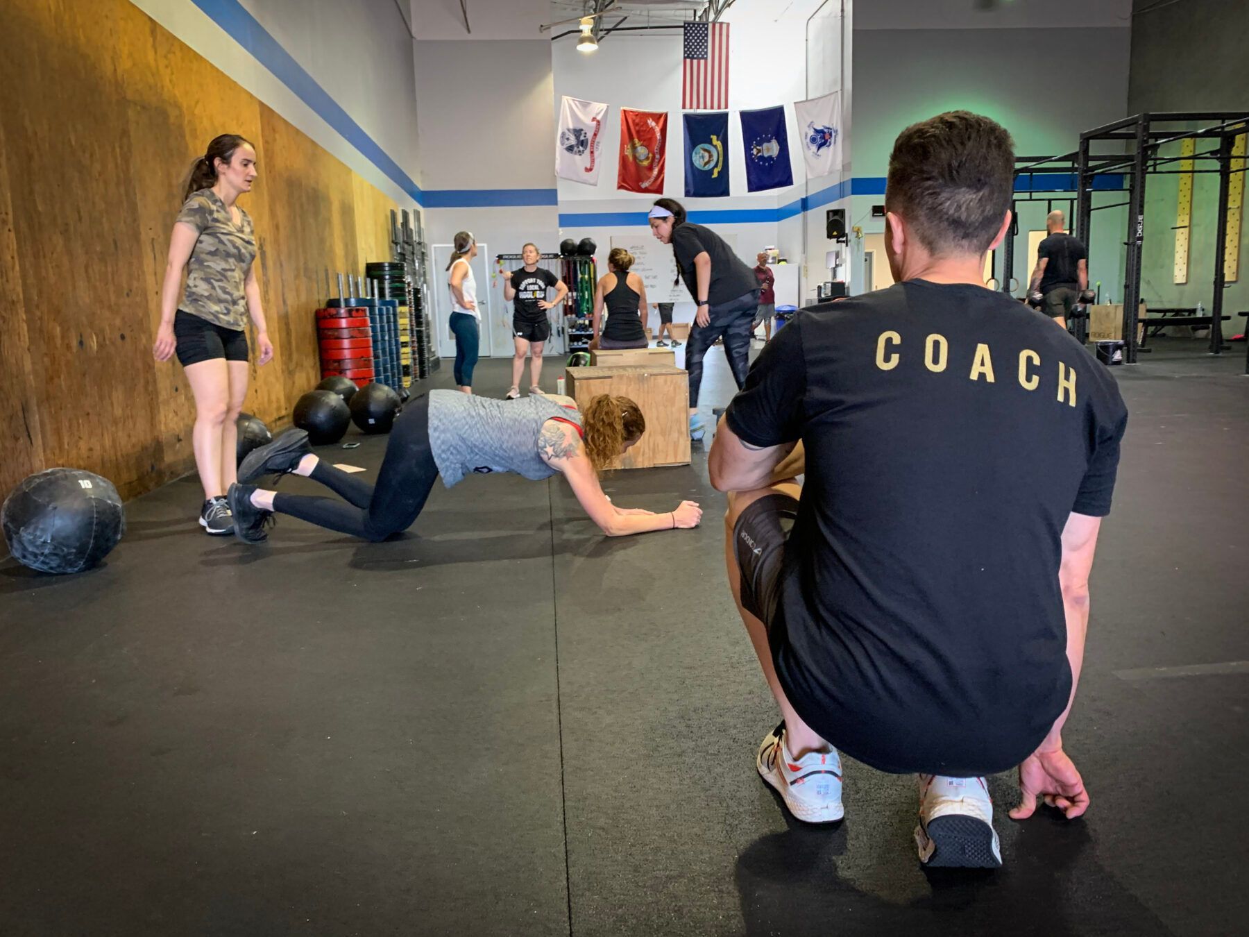 Coach watches athletes doing floor exercises in Iron Grip CrossFit, a gym in Tucson, AZ