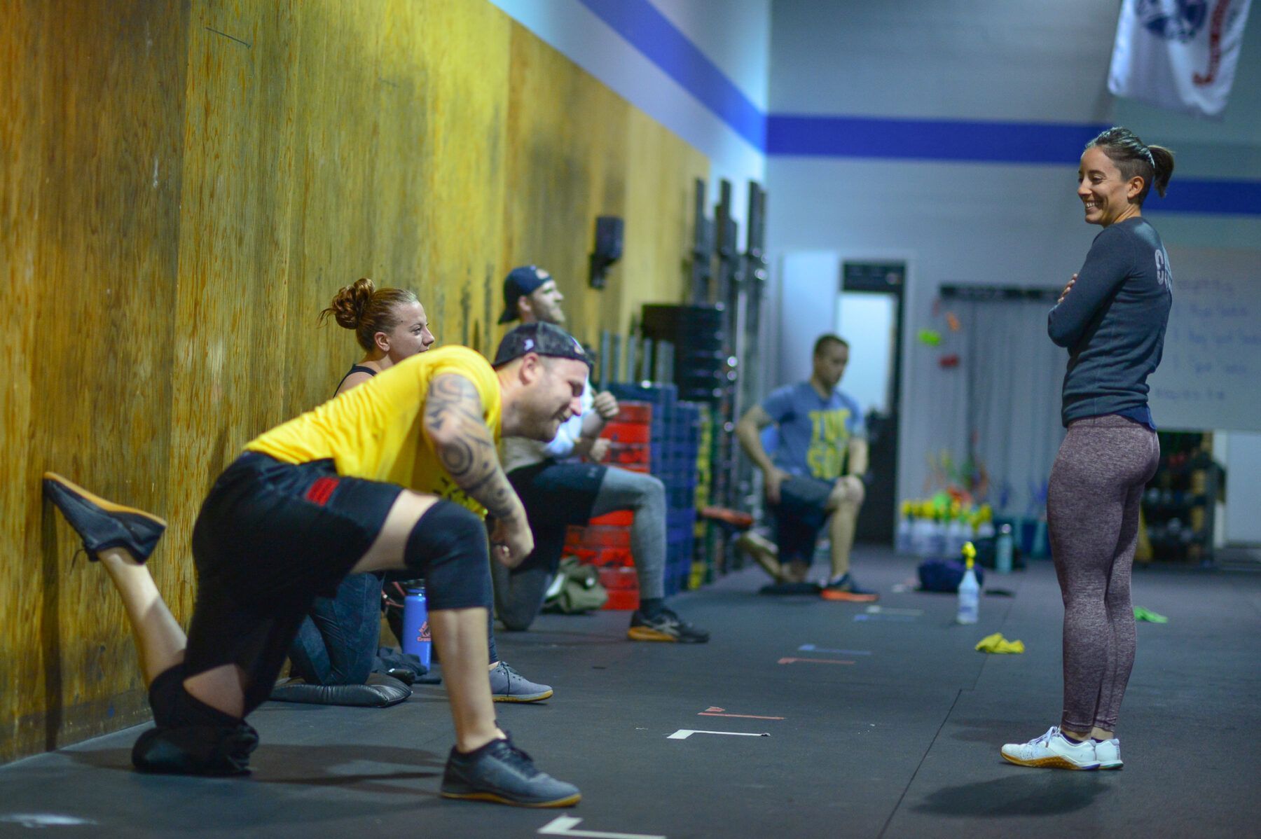 People stretching in Iron Grip CrossFit, a gym in Tucson, AZ, with a coach standing nearby.