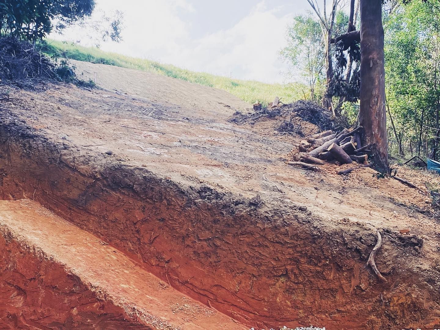 An Excavator Loading A White Dump Truck With Red Soil On A Sunny Day  — Lifestyle Demolition In Lismore, NSW