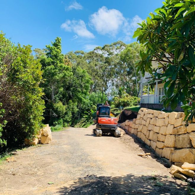 An Orange Excavator on A Gravel Road — Lifestyle Demolition In Lismore, NSW