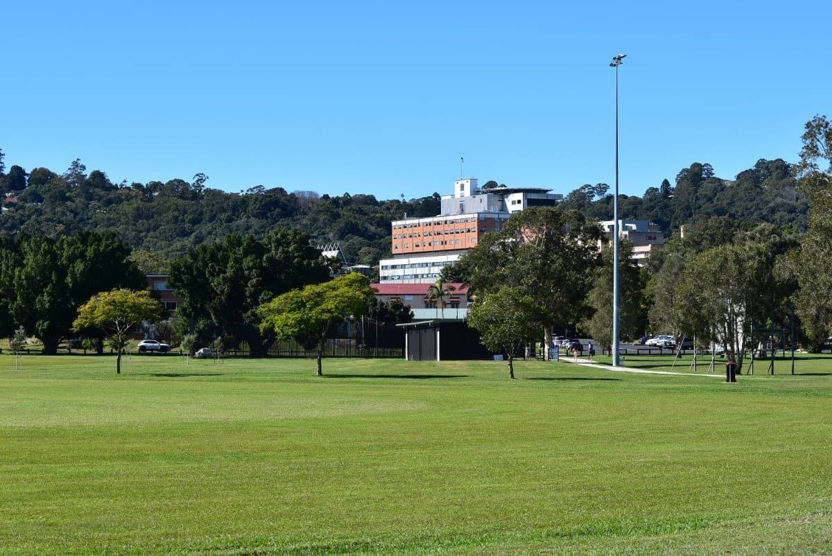 A Large Grassy Field with Trees and A Building in The Background — Lifestyle Demolition In Lismore, NSW