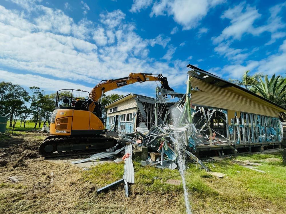 A Yellow Excavator Is Digging a Hole in The Dirt — Lifestyle Demolition In Lismore, NSW