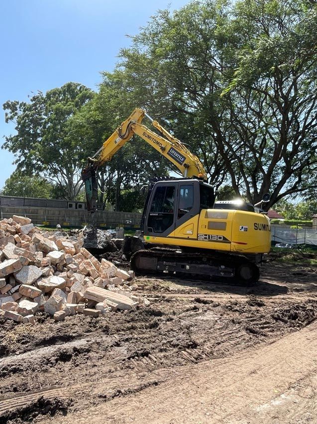 A Yellow Excavator Is Digging a Hole in The Ground — Lifestyle Demolition in Kingscliff, NSW