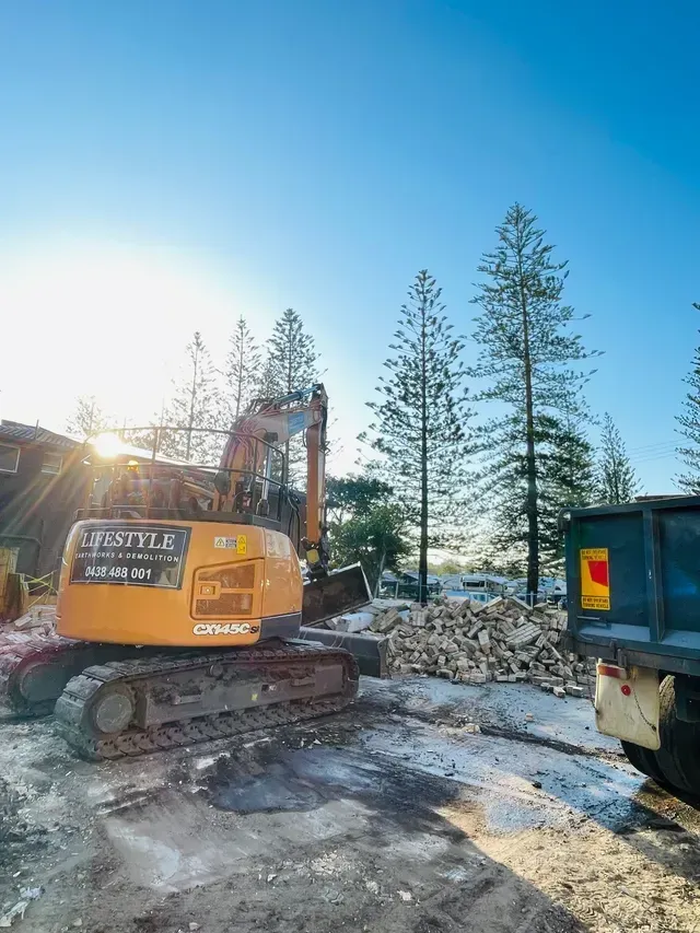 An Excavator Is Sitting in The Middle of A Dirt Field — Lifestyle Demolition in Kingscliff, NSW