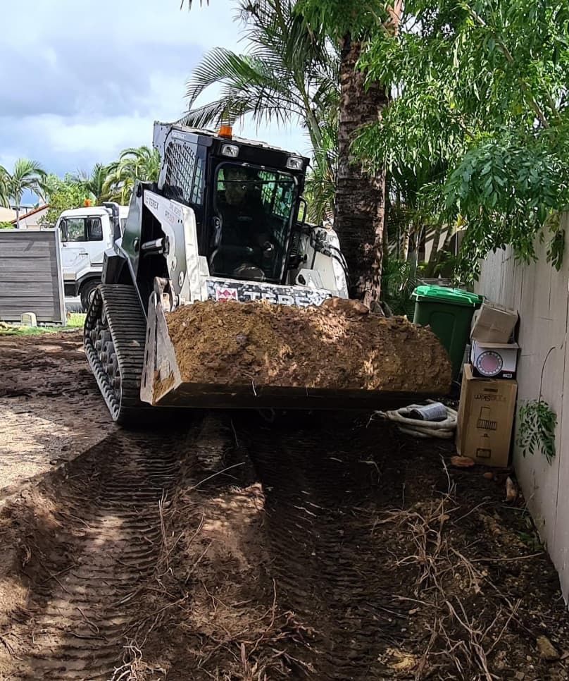 A White Bobcat Skid Steer With A Dirt-filled Bucket Is On A Muddy Construction Site — Lifestyle Demolition In Ballina, NSW