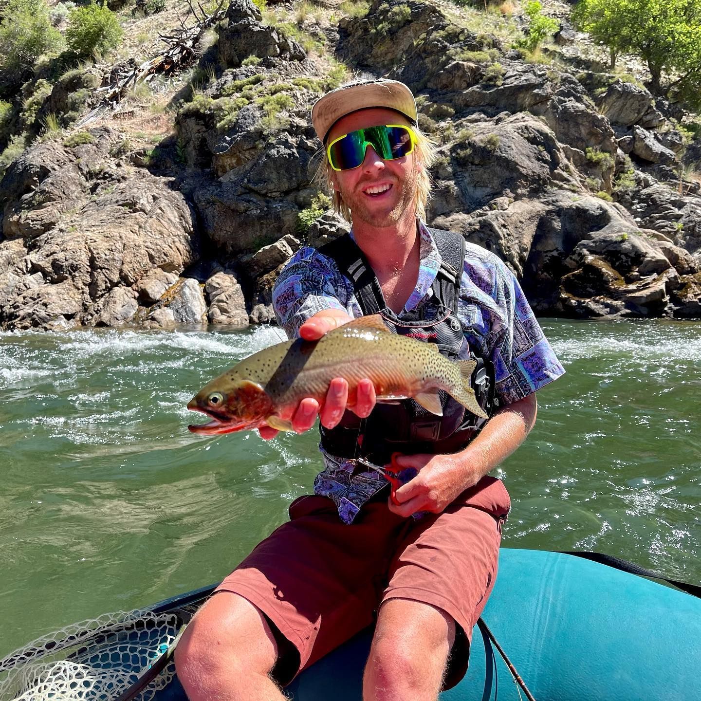 A man is sitting on a raft holding a fish in his hands.