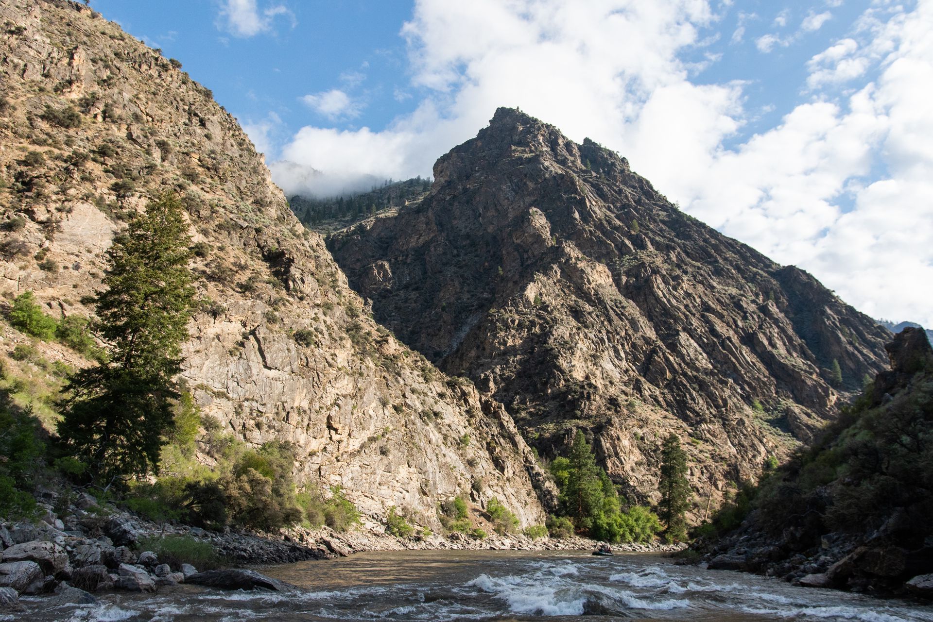 A river flowing through a canyon with mountains in the background