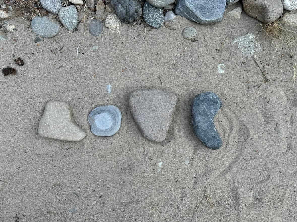 The word love is written on the sand with rocks