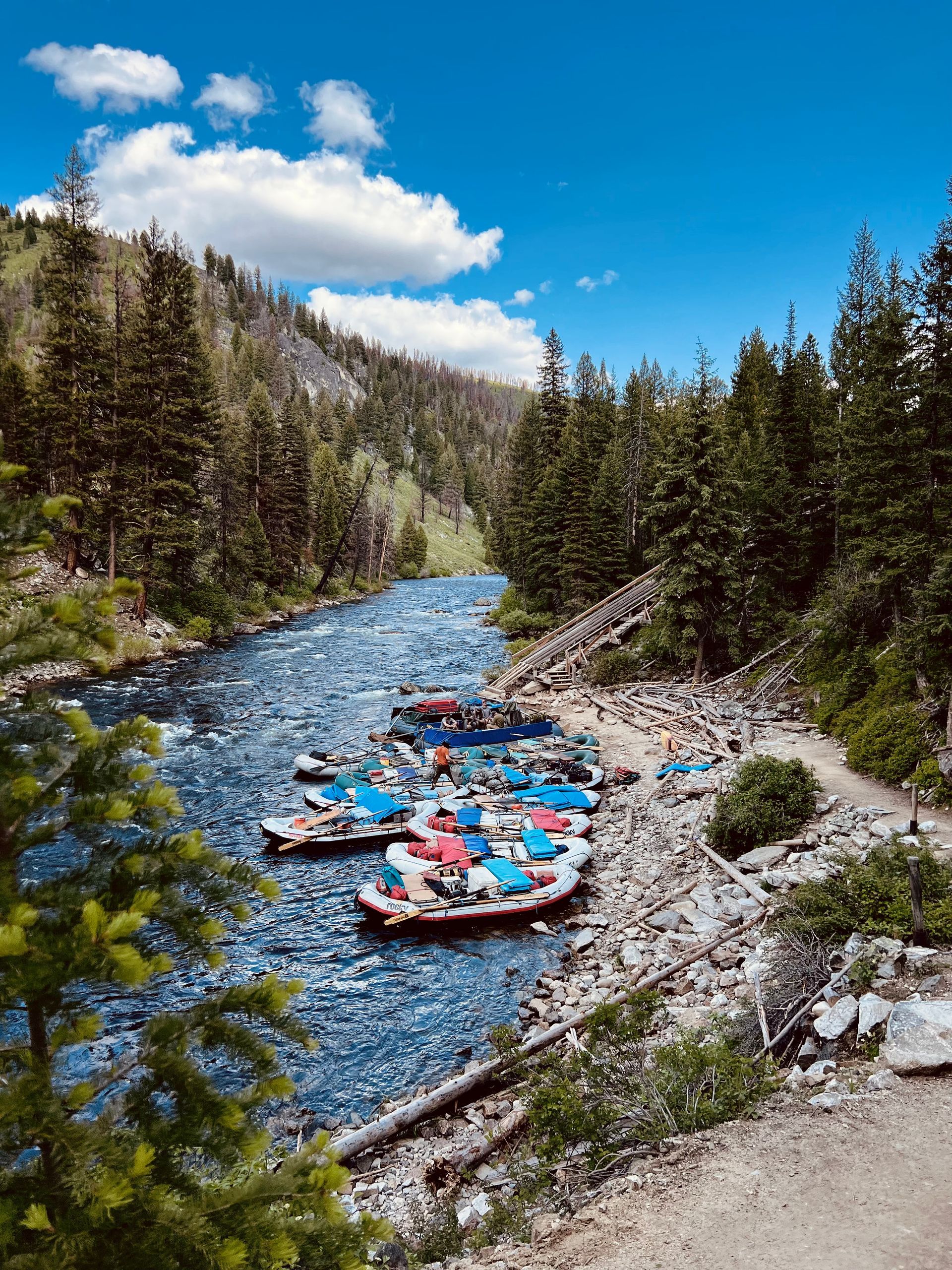 A group of rafts are sitting on the shore of a river.