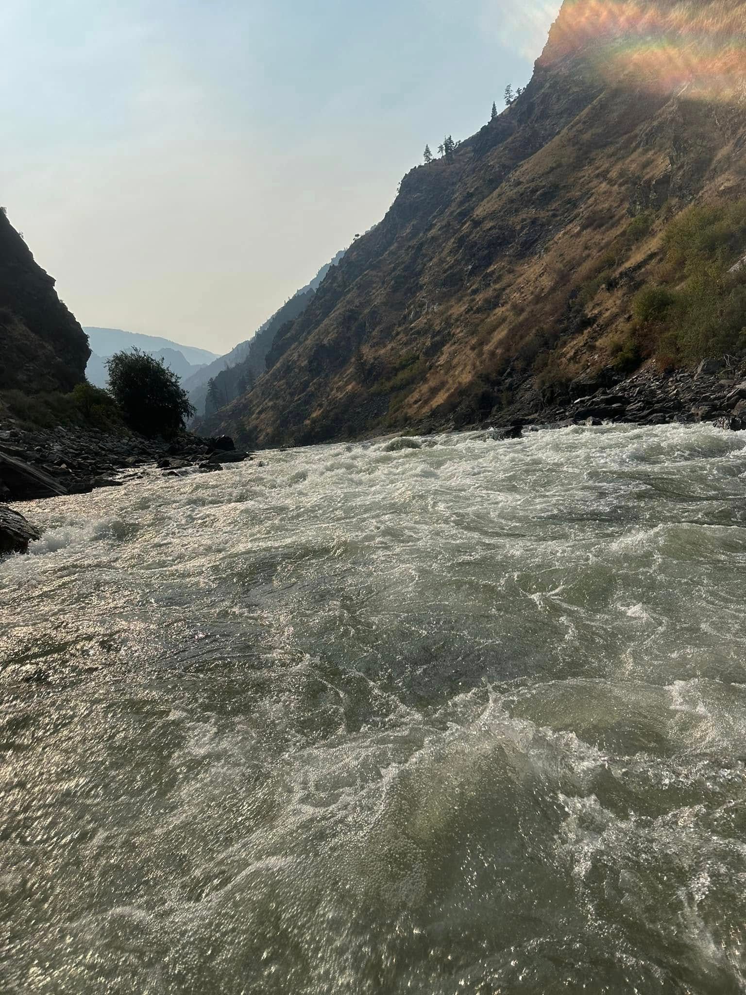 A river flowing through a canyon with mountains in the background.