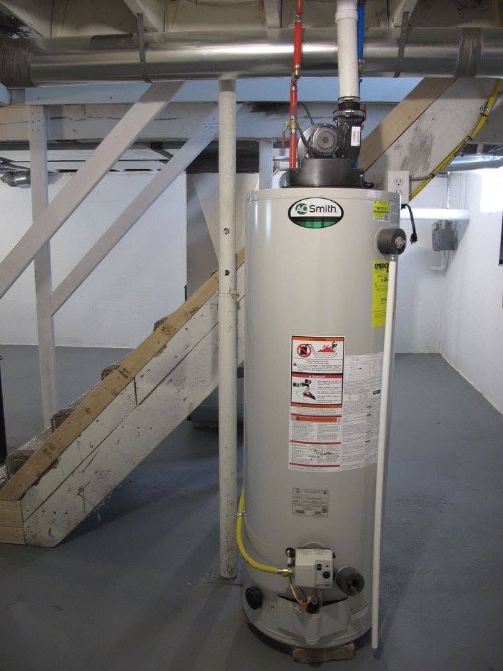 Gray water heater in a basement with pipes, stairs, and utility lines nearby
