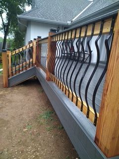 Wooden deck with gray siding and decorative black metal railings.