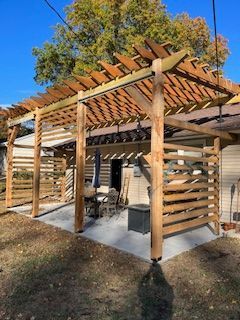Wooden pergola over a patio with horizontal slatted privacy screens.