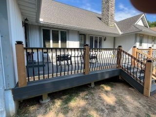 Back deck with black railing and light gray siding on a house.