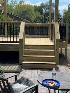 Wooden deck with stairs, black railing, and outdoor furniture.