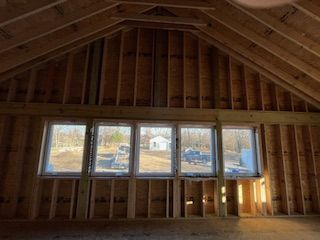 Interior of unfinished attic with windows and exposed wooden beams.
