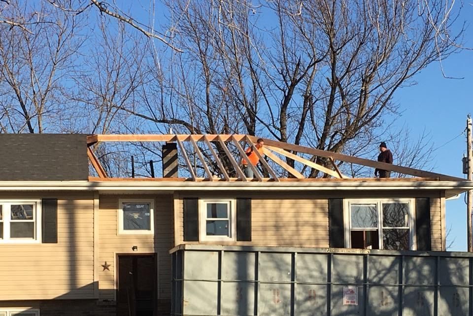 Construction workers building a new roof frame on a two-story house.
