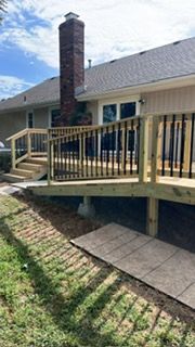 A wooden deck with black railings and a brick chimney attached to a house.