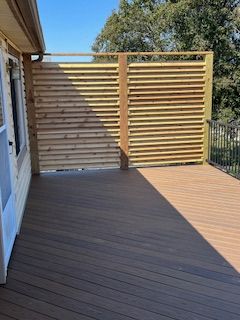 Wooden deck with horizontal slat privacy screen. Brown composite decking.