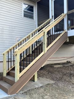 Outdoor staircase with brown ramp for accessibility. Light siding, railings, and steps.