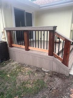 Deck with composite siding and railing, black balusters, and stained wooden posts and handrails.