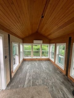 Wooden-ceilinged room with gray wood-look floor, windows along one wall.
