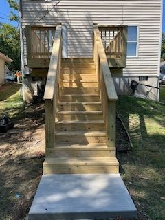 Wooden staircase leading up to a house with a concrete landing.