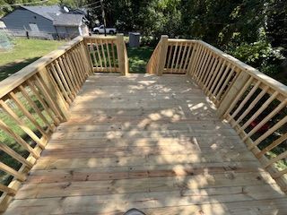 Wooden deck with railings, steps down to yard, sunny day.