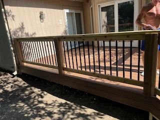 Wooden deck with black railings; a person is on the deck near the door.