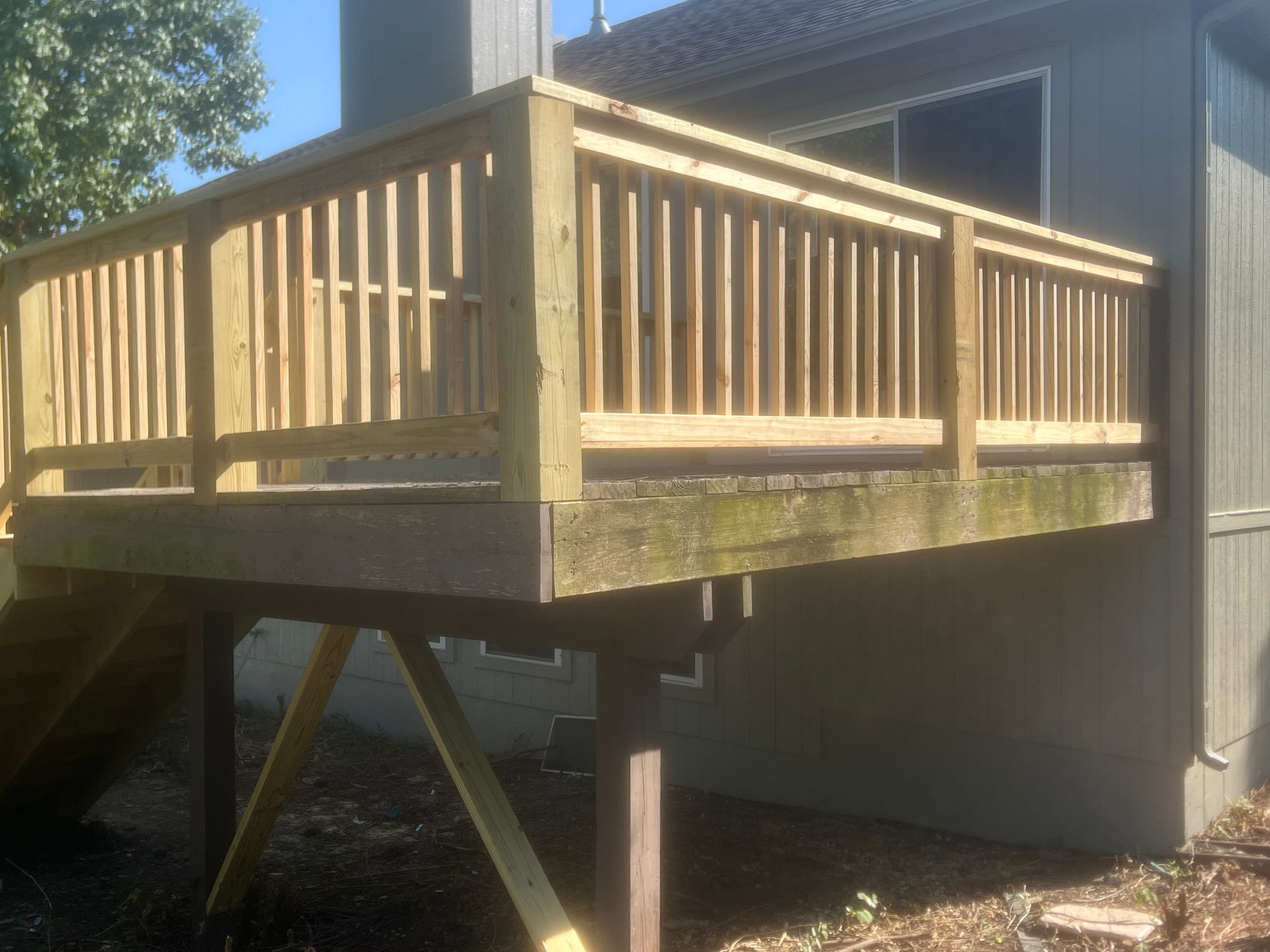 Wooden deck with new railing attached to a building's exterior.