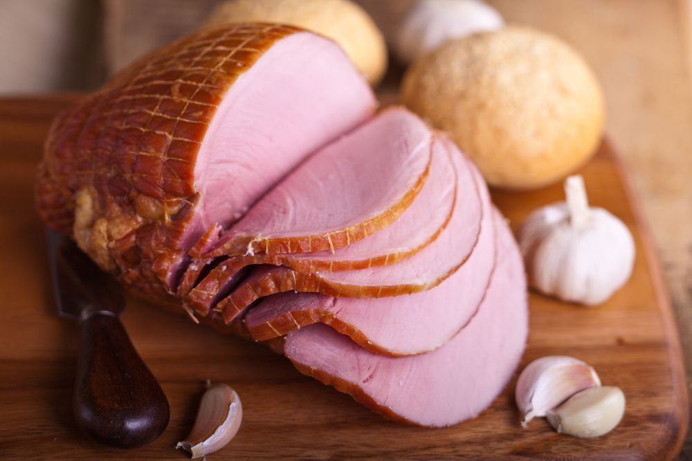 A Sliced Ham is Sitting on a Wooden Cutting Board — Corrado & Frank Distributors in Fairy Meadow, NSW