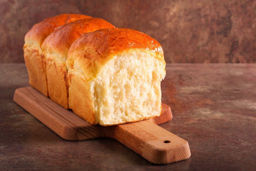 A Loaf of Bread is Sitting on a Wooden Cutting Board — Corrado & Frank Distributors in Fairy Meadow, NSW