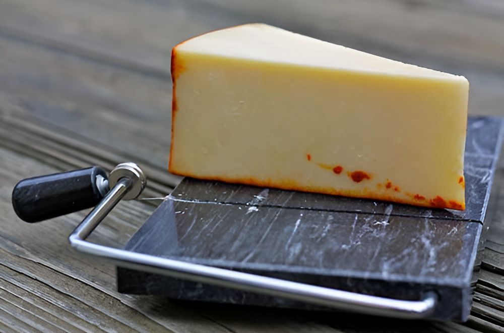A Piece of Cheese is Sitting on a Marble Cutting Board — Corrado & Frank Distributors in Fairy Meadow, NSW