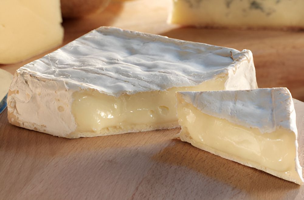 A Piece of Cheese is Cut in Half on a Wooden Cutting Board — Corrado & Frank Distributors in Fairy Meadow, NSW