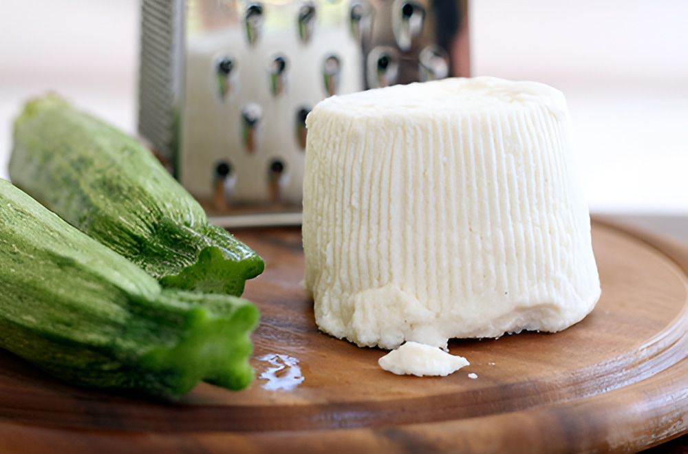 A Piece of Cheese is Sitting on a Wooden Cutting Board — Corrado & Frank Distributors in Fairy Meadow, NSW