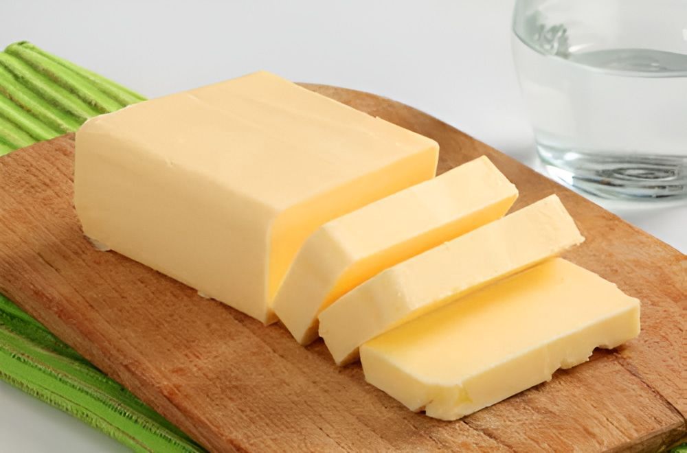 A Piece of Butter is Sitting on a Wooden Cutting Board — Corrado & Frank Distributors in Fairy Meadow, NSW