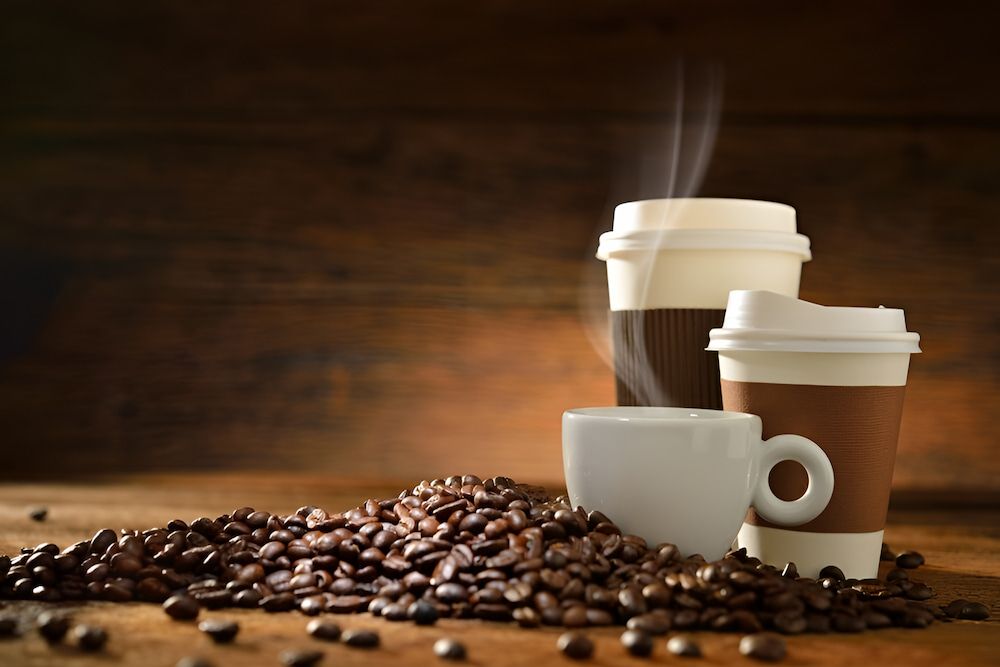 Three Cups of Coffee and a Pile of Coffee Beans on a Wooden Table — Corrado & Frank Distributors in Fairy Meadow, NSW