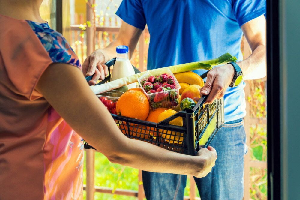 A Man is Delivering a Basket of Fruits and Vegetables to a Woman — Corrado & Frank Distributors in Mittagong, NSW
