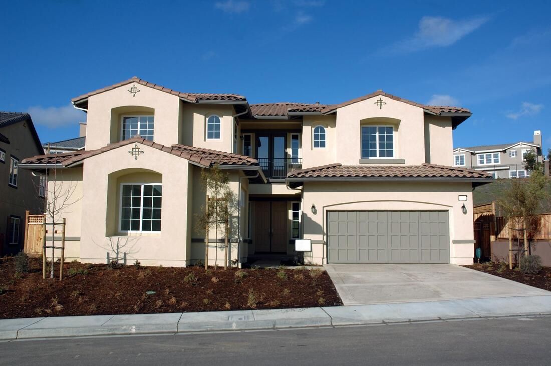 Driveway installation by Maple Ridge Concrete. The pattern is sawcut and the picture is taken from the street view of the front of the beige house.