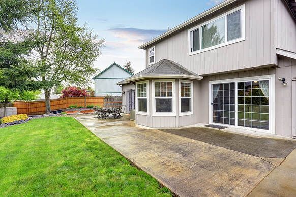 Maple Ridge Concrete backyard patio installation beside a grey house.