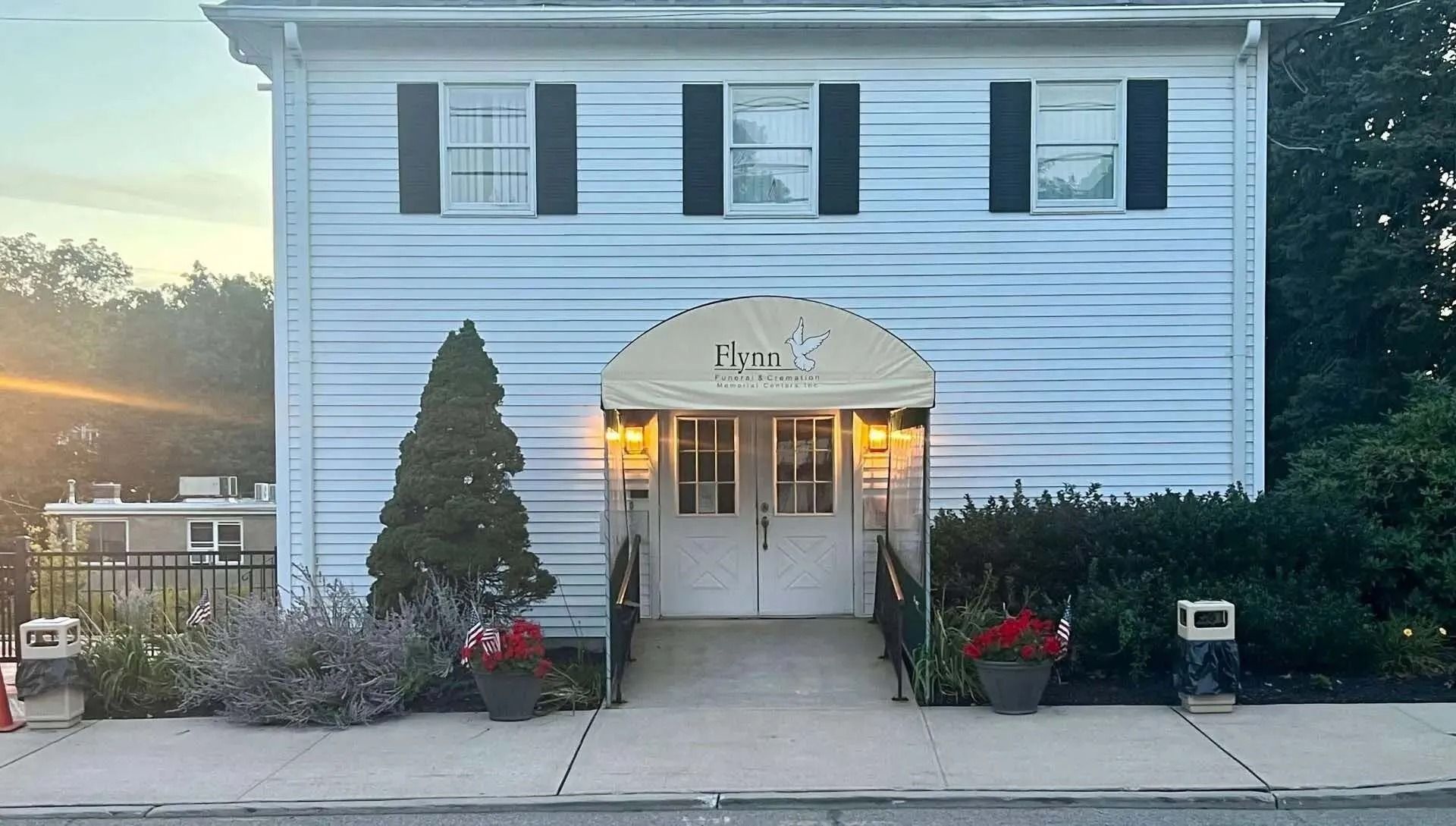 White building with black shutters, arched awning reading 