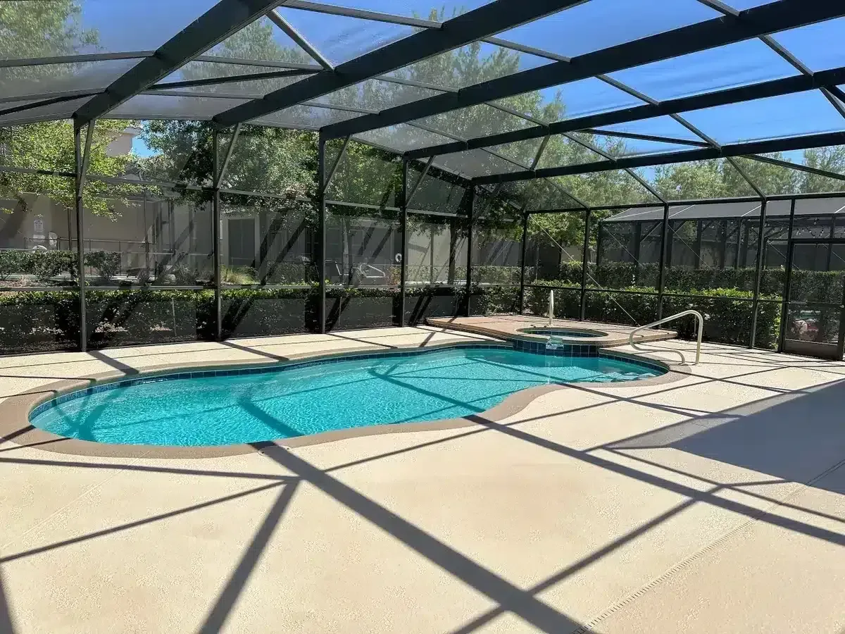 Screened backyard pool with a tan deck and clear blue water in sunlight