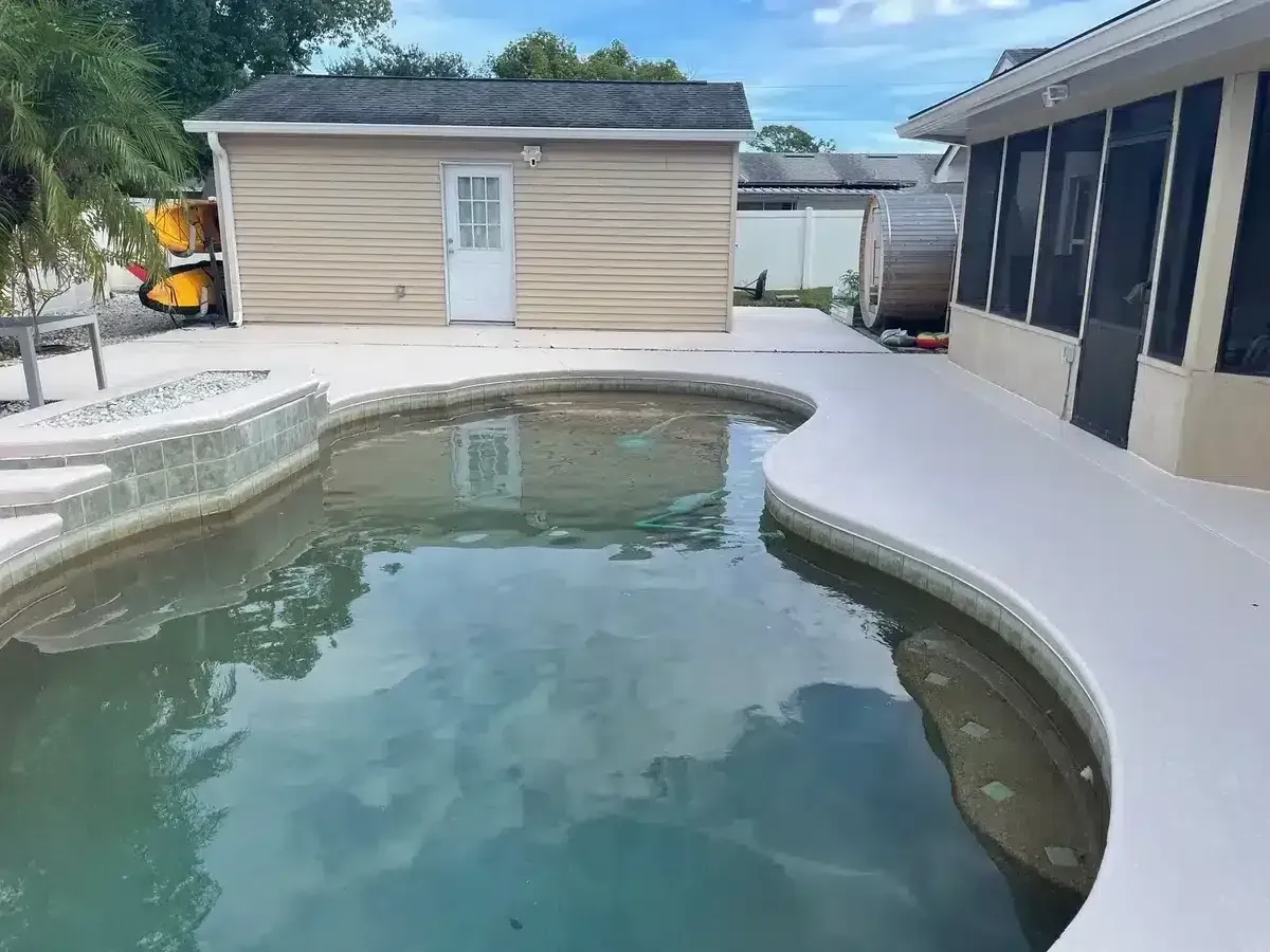 Backyard swimming pool with light blue water beside a beige shed and screened patio area