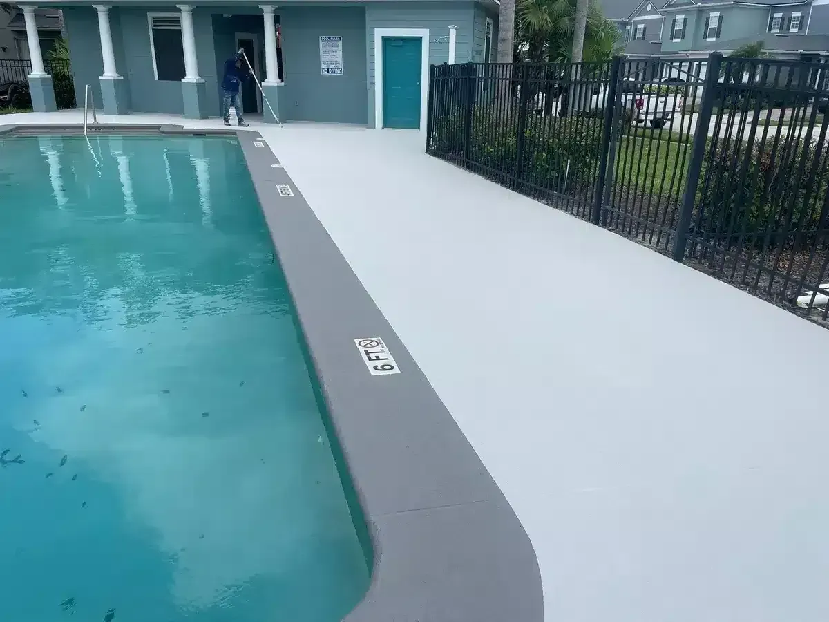 Swimming pool deck with a wheelchair-accessible ramp and black fence along the side