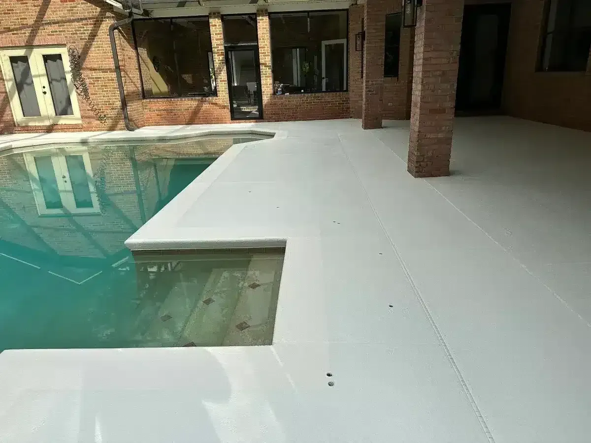 Brick courtyard with a white patio and a turquoise swimming pool