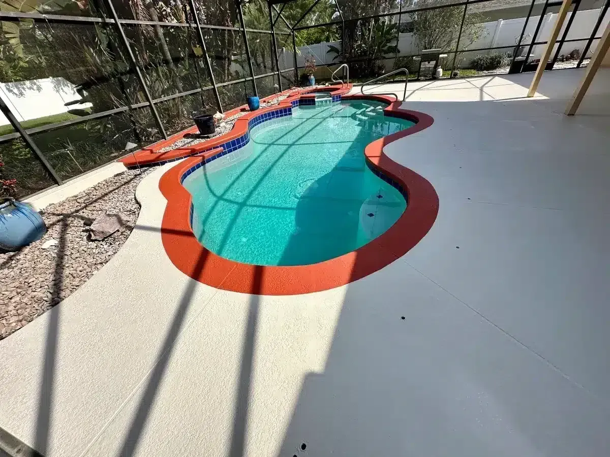 Backyard swimming pool with red coping and turquoise water in bright sunlight