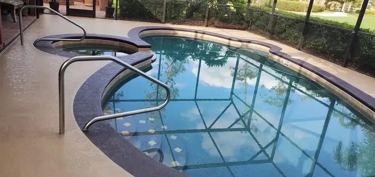 Curved backyard swimming pool with a bent handrail and its reflection in the water