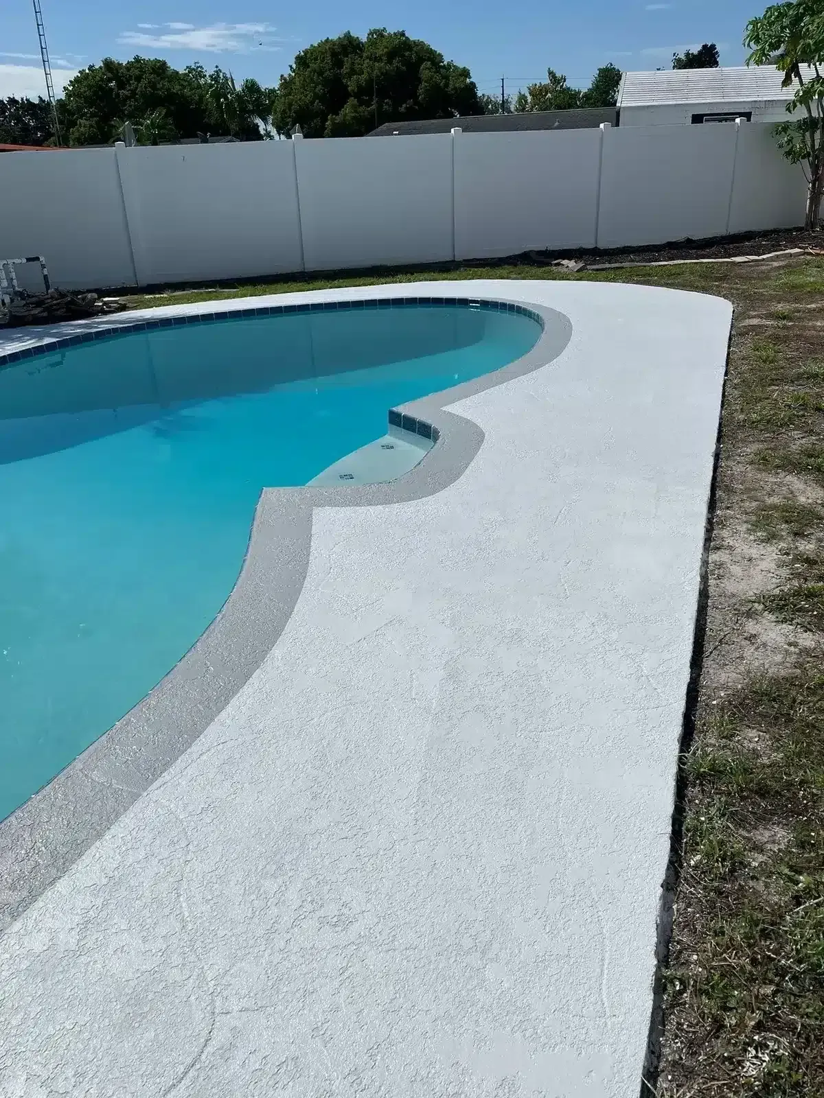 Blue-tiled pool with a central water fountain and stone coping under a sunny sky